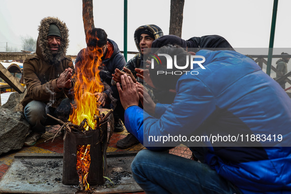 People warm themselves by a bonfire on a cold winter morning at Dal Lake in Srinagar, Jammu and Kashmir, India, on December 20, 2024. Srinag...