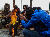 People warm themselves by a bonfire on a cold winter morning at Dal Lake in Srinagar, Jammu and Kashmir, India, on December 20, 2024. Srinag...