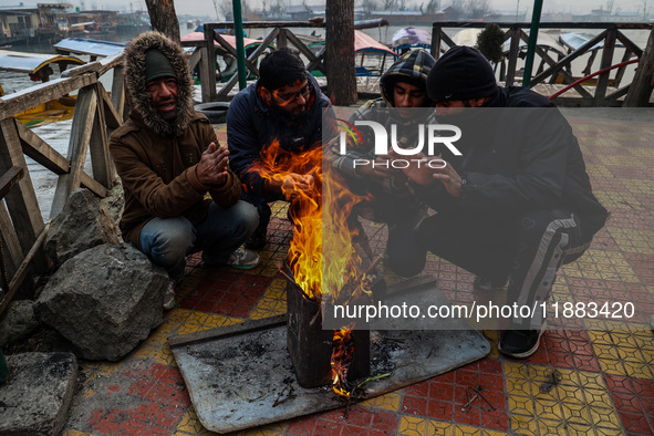 People warm themselves by a bonfire on a cold winter morning at Dal Lake in Srinagar, Jammu and Kashmir, India, on December 20, 2024. Srinag...