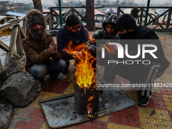 People warm themselves by a bonfire on a cold winter morning at Dal Lake in Srinagar, Jammu and Kashmir, India, on December 20, 2024. Srinag...