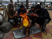 People warm themselves by a bonfire on a cold winter morning at Dal Lake in Srinagar, Jammu and Kashmir, India, on December 20, 2024. Srinag...