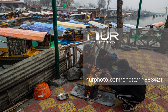 People warm themselves by a bonfire on a cold winter morning at Dal Lake in Srinagar, Jammu and Kashmir, India, on December 20, 2024. Srinag...