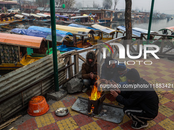 People warm themselves by a bonfire on a cold winter morning at Dal Lake in Srinagar, Jammu and Kashmir, India, on December 20, 2024. Srinag...