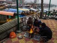 People warm themselves by a bonfire on a cold winter morning at Dal Lake in Srinagar, Jammu and Kashmir, India, on December 20, 2024. Srinag...