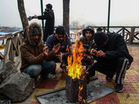 People warm themselves by a bonfire on a cold winter morning at Dal Lake in Srinagar, Jammu and Kashmir, India, on December 20, 2024. Srinag...