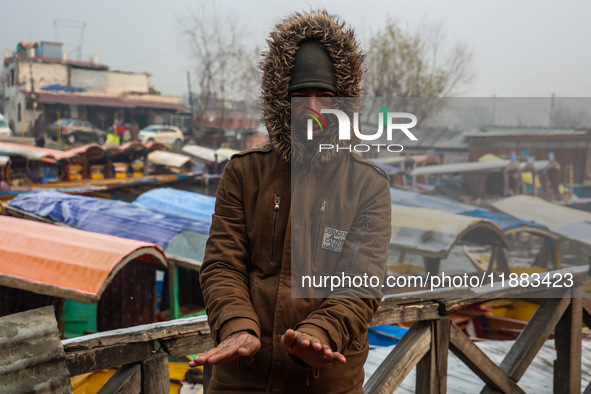 People warm themselves by a bonfire on a cold winter morning at Dal Lake in Srinagar, Jammu and Kashmir, India, on December 20, 2024. Srinag...