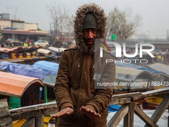 People warm themselves by a bonfire on a cold winter morning at Dal Lake in Srinagar, Jammu and Kashmir, India, on December 20, 2024. Srinag...