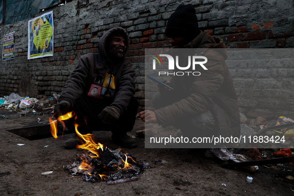 People warm themselves by a bonfire on a cold winter morning at Dal Lake in Srinagar, Jammu and Kashmir, India, on December 20, 2024. Srinag...