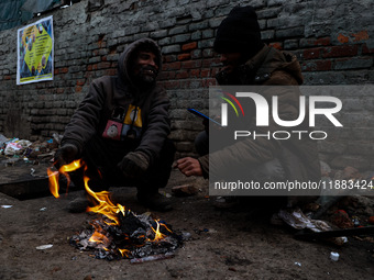 People warm themselves by a bonfire on a cold winter morning at Dal Lake in Srinagar, Jammu and Kashmir, India, on December 20, 2024. Srinag...