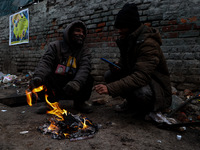 People warm themselves by a bonfire on a cold winter morning at Dal Lake in Srinagar, Jammu and Kashmir, India, on December 20, 2024. Srinag...