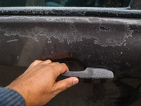 A person tries to open a frosted car door on a cold day in Srinagar, Jammu and Kashmir, India, on December 20, 2024. (