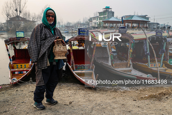 A shikara owner warms himself with a Kangri (firepot) on a cold day in Srinagar, Jammu and Kashmir, India, on December 20, 2024. 