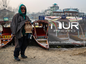 A shikara owner warms himself with a Kangri (firepot) on a cold day in Srinagar, Jammu and Kashmir, India, on December 20, 2024. (