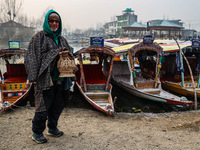 A shikara owner warms himself with a Kangri (firepot) on a cold day in Srinagar, Jammu and Kashmir, India, on December 20, 2024. (