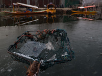 A fisherman shows sheets of ice formed due to cold weather at Dal Lake in Srinagar, Jammu and Kashmir, India, on December 20, 2024. (