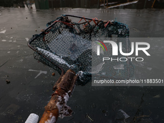 A fisherman shows sheets of ice formed due to cold weather at Dal Lake in Srinagar, Jammu and Kashmir, India, on December 20, 2024. (