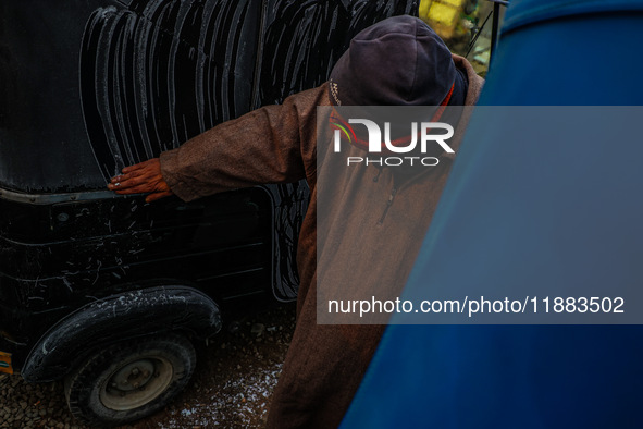 A rickshaw driver clears frost from an auto due to cold weather in Srinagar, Jammu and Kashmir, India, on December 20, 2024. 