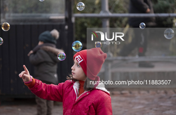 A young Iranian girl plays with soap bubbles in the Abasabad tourism zone in central Tehran, Iran, on December 19, 2024. 