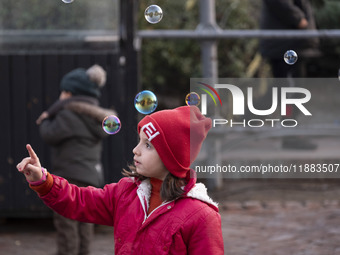 A young Iranian girl plays with soap bubbles in the Abasabad tourism zone in central Tehran, Iran, on December 19, 2024. (