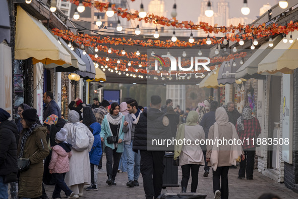 Iranian people walk past food stands while visiting the Abasabad tourism zone in central Tehran, Iran, on December 19, 2024. 