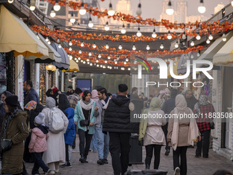 Iranian people walk past food stands while visiting the Abasabad tourism zone in central Tehran, Iran, on December 19, 2024. (