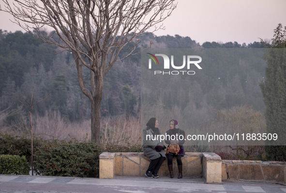 Two Iranian women sit together while visiting the Abasabad tourism zone in central Tehran, Iran, on December 19, 2024. 