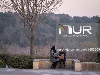 Two Iranian women sit together while visiting the Abasabad tourism zone in central Tehran, Iran, on December 19, 2024. (