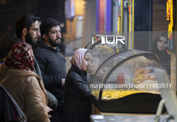 A young Iranian girl waits to receive french fries while visiting the Abasabad tourism zone in central Tehran, Iran, on December 19, 2024. 