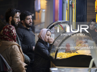 A young Iranian girl waits to receive french fries while visiting the Abasabad tourism zone in central Tehran, Iran, on December 19, 2024. (