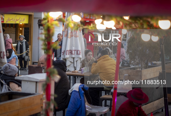 Iranian youths sit together at an outdoor fast-food restaurant while visiting the Abasabad tourism zone in central Tehran, Iran, on December...