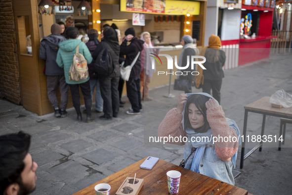 Iranian youths sit together at an outdoor fast-food restaurant while visiting the Abasabad tourism zone in central Tehran, Iran, on December...