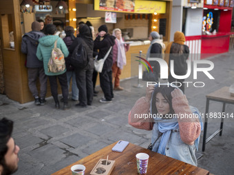 Iranian youths sit together at an outdoor fast-food restaurant while visiting the Abasabad tourism zone in central Tehran, Iran, on December...