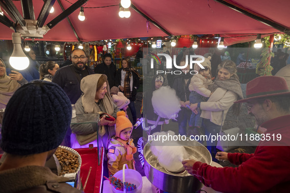 A young Iranian girl receives a traditional sweet while visiting the Abasabad tourism zone with her parents in central Tehran, Iran, on Dece...