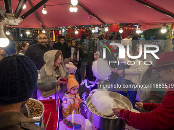 A young Iranian girl receives a traditional sweet while visiting the Abasabad tourism zone with her parents in central Tehran, Iran, on Dece...