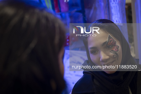 A young Iranian woman with a painting on her face smiles while participating in a festival in the Abasabad tourism zone in central Tehran, I...