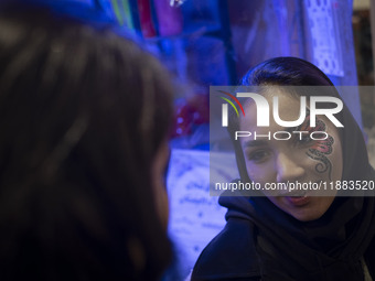 A young Iranian woman with a painting on her face smiles while participating in a festival in the Abasabad tourism zone in central Tehran, I...