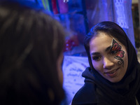 A young Iranian woman with a painting on her face smiles while participating in a festival in the Abasabad tourism zone in central Tehran, I...