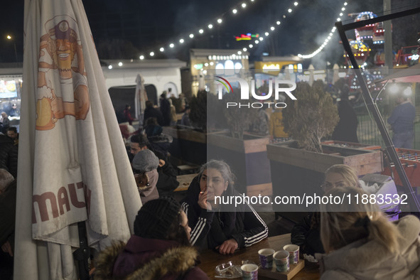 Iranian women sit together at an outdoor fast-food restaurant while visiting the Abasabad tourism zone in central Tehran, Iran, on December...