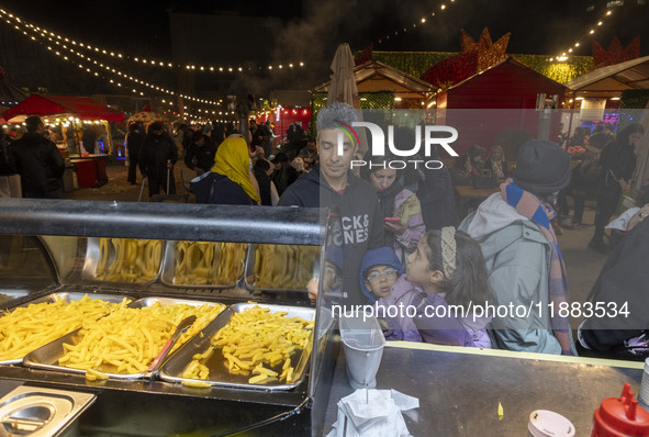 An Iranian family waits to receive french fries while visiting the Abasabad tourism zone in central Tehran, Iran, on December 19, 2024. 