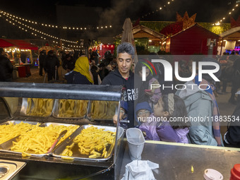 An Iranian family waits to receive french fries while visiting the Abasabad tourism zone in central Tehran, Iran, on December 19, 2024. (