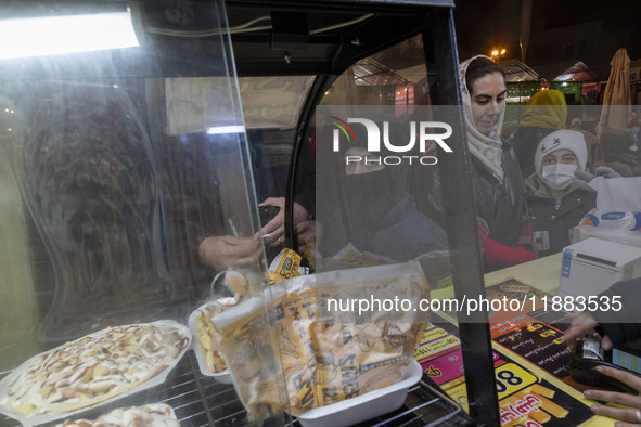 A young Iranian boy waits to receive pizza in the Abasabad tourism zone in central Tehran, Iran, on December 19, 2024. 