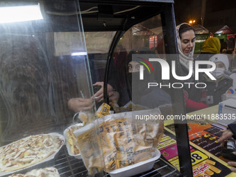 A young Iranian boy waits to receive pizza in the Abasabad tourism zone in central Tehran, Iran, on December 19, 2024. (