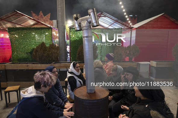 Iranian women sit together around an old heater while visiting the Abasabad tourism zone in central Tehran, Iran, on December 19, 2024. 