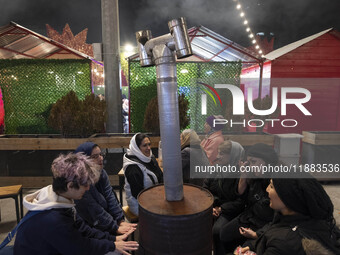 Iranian women sit together around an old heater while visiting the Abasabad tourism zone in central Tehran, Iran, on December 19, 2024. (