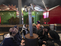 Iranian women sit together around an old heater while visiting the Abasabad tourism zone in central Tehran, Iran, on December 19, 2024. (