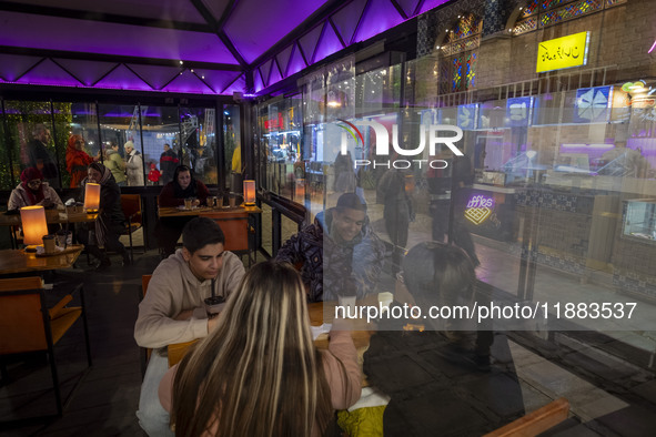 Iranian youths sit together at a cafe while visiting the Abasabad tourism zone in central Tehran, Iran, on December 19, 2024. 