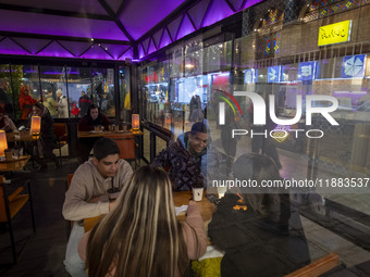 Iranian youths sit together at a cafe while visiting the Abasabad tourism zone in central Tehran, Iran, on December 19, 2024. (