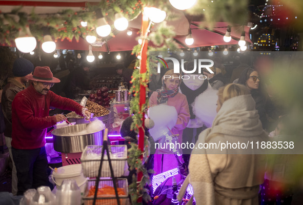 A young Iranian girl waits to receive a traditional sweet while visiting the Abasabad tourism zone with her parents in central Tehran, Iran,...