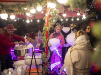 A young Iranian girl waits to receive a traditional sweet while visiting the Abasabad tourism zone with her parents in central Tehran, Iran,...