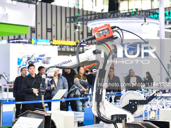 People visit and exhibit industrial robots at the 2024 World Intelligent Manufacturing Conference in Nanjing, Jiangsu Province, China, on De...